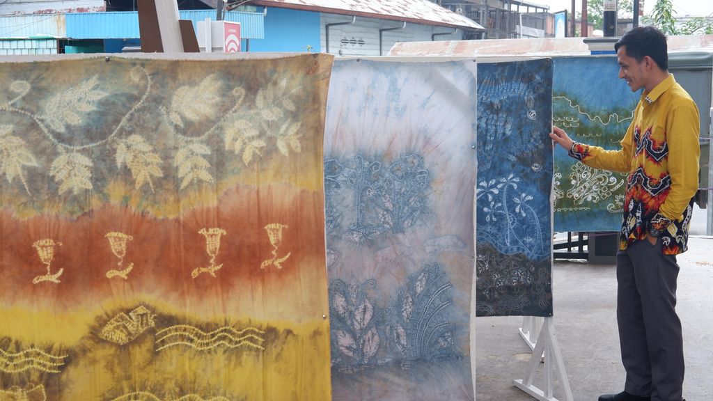 Seorang pengunjung memperhatikan kain sasirangan dengan pewarnaan alami yang dipajang dalam kegiatan Lomba Desain Motif Sasirangan Se-Kota Banjarmasin di Banjarmasin, Kalimantan Selatan, Kamis (5/3/2020). 