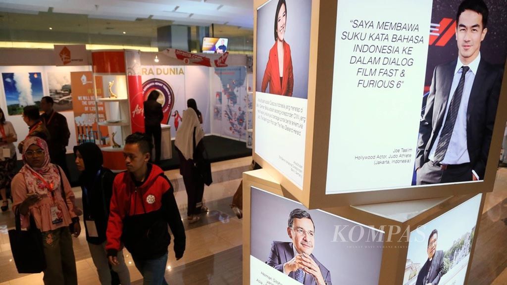 Pengunjung Kongres Diaspora Indonesia ke-4 melintas di samping potret wajah-wajah diaspora Indonesia yang ditampilkan di lokasi kongres di Jakarta, Jumat (1/7/2018). 