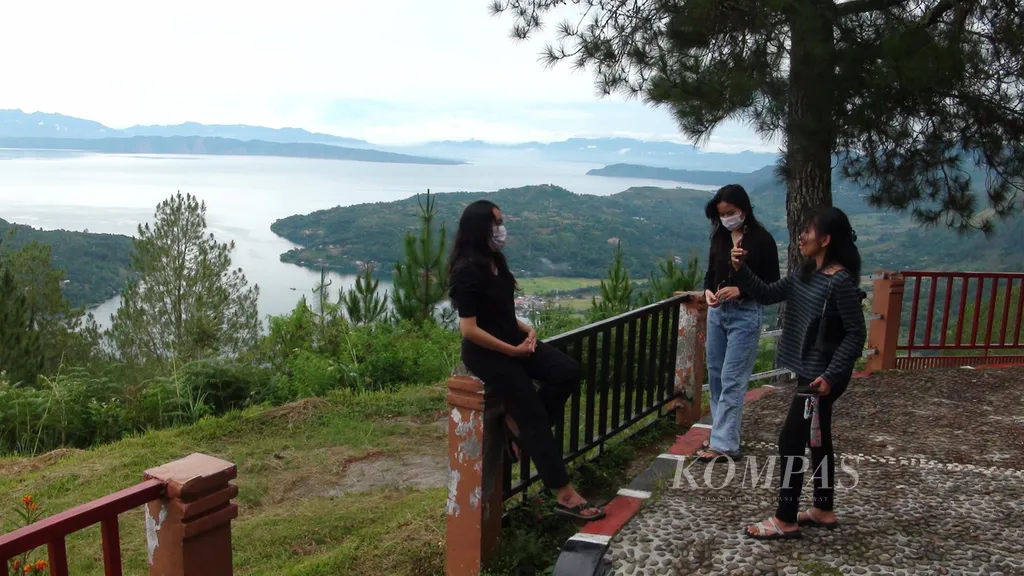 Wisatawan menikmati keindahan bentang alam Taman Bumi Kaldera Toba dari Geosite Sipinsur di Kabupaten Humbang Hasundutan, Sumatera Utara, Sabtu (21/12/2024).