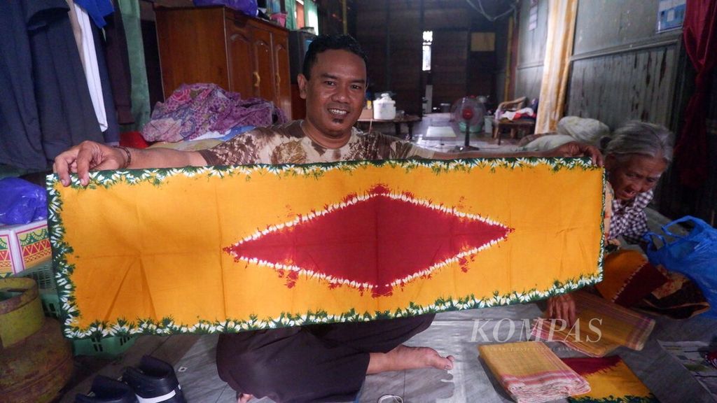 Riza Aspihany (44), perajin kain sasirangan, memperlihatkan kain pamintan buatan seorang perajin senior di Kampung Sasirangan, Kelurahan Seberang Mesjid, Kecamatan Banjarmasin Tengah, Kota Banjarmasin, Kalimantan Selatan, Rabu (21/9/2022). Kain pamintan merupakan kain khas suku Banjar untuk pengobatan secara tradisional, yang kemudian diinovasikan menjadi kain sasirangan.