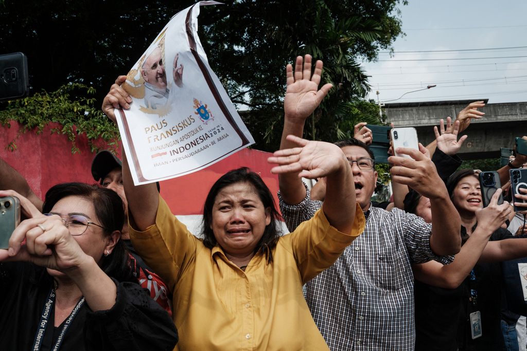Warga melambai ke kendaraan Paus Fransiskus di dekat kedutaan Vatikan di Jakarta (4/9/2024). Kunjungan Paus Fransiskus mengobati kerinduan rohani umat Katolik Indonesia.