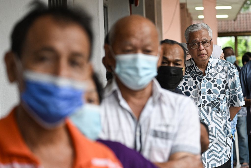 Perdana Menteri Malaysia Ismail Sabri Yakob (berdiri paling belakang) mengantre bersama sejumlah warga lain di tempat pemungutan suara di Bera, Negara Bagian Pahang, Malaysia, Sabtu (19/11/2022). 