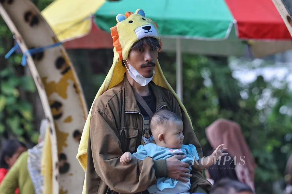 Seorang ayah membawa anaknya di Kebun Binatang Ragunan di Jakarta pada 25 Januari 2024. Kebun Binatang Ragunan dipenuhi pengunjung selama liburan Natal tahun 2024.