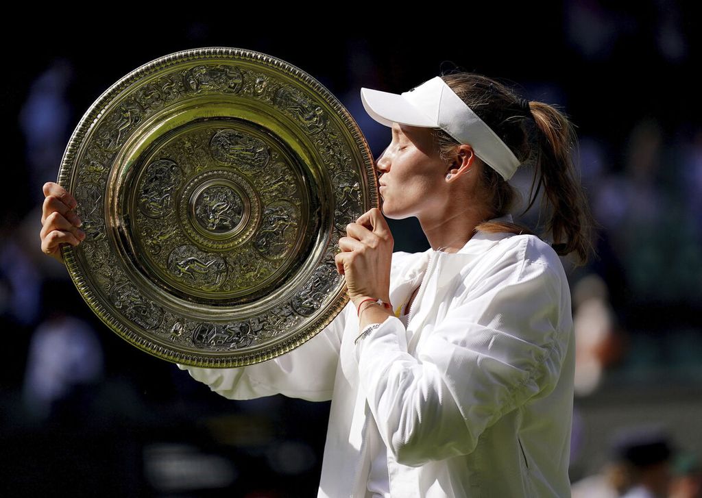 Elena Rybakina, petenis asal Rusia yang membela Kazakhstan, mencium trofi juara seusai mengalahkan Ons Jabeur (Tunisia) pada final tunggal putri Wimbledon 2022 di All England Tennis Club, London, Sabtu (9/7/2022). Rybakina menang, 3-6, 6-2, 6-2. 
