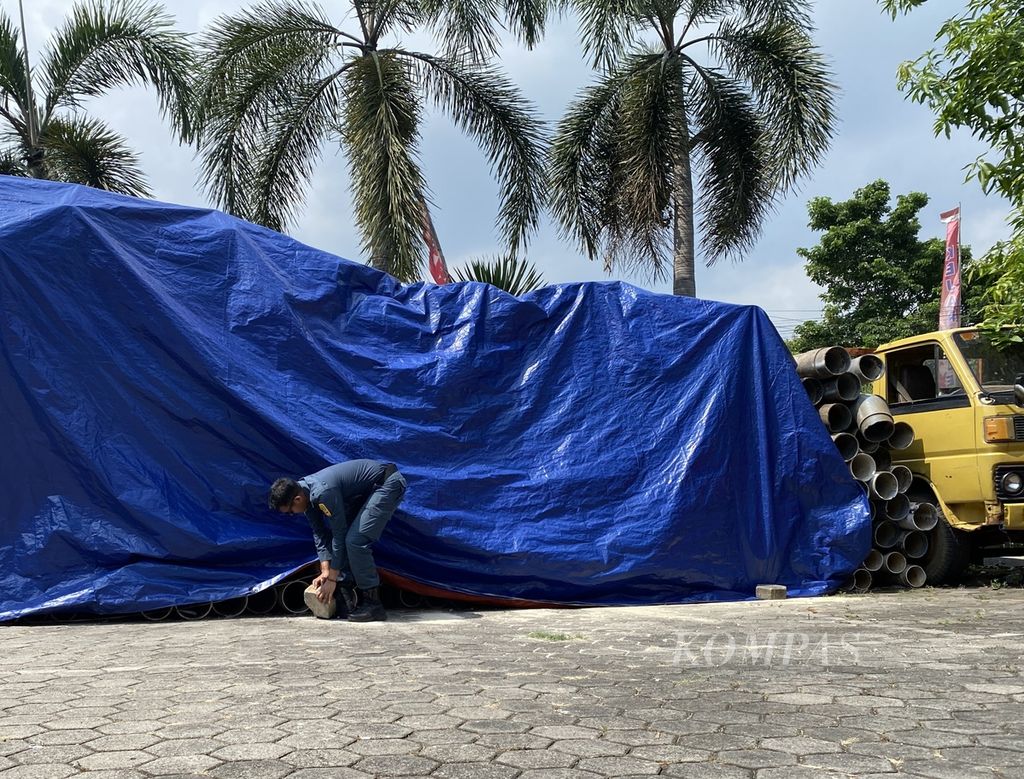Petugas menutup ratusan pipa dengan terpal di halaman Kejaksaan Negeri Jepara, Jawa Tengah, Kamis (13/6/2024). 