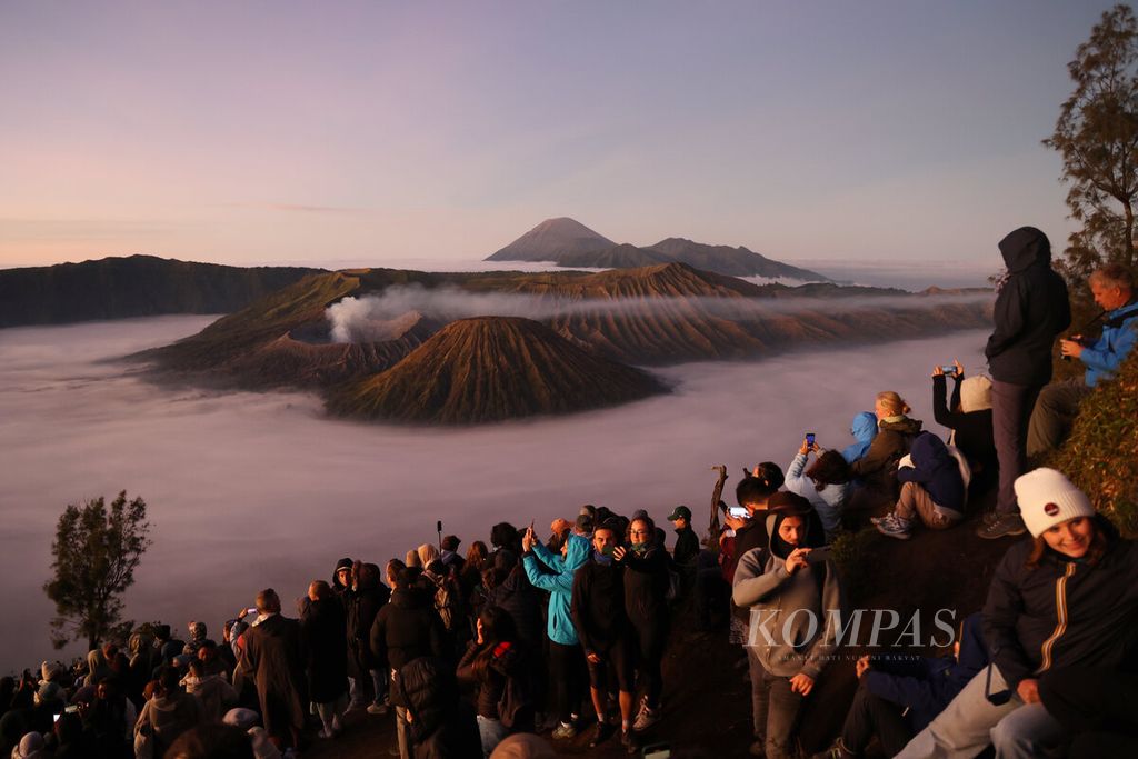 Wisatawan mancanegara dan domestik saat menikmati keindahan matahari terbit dari Bukit Kedaluh, Taman Nasional Bromo Tengger Semeru (TNBTS) di Kabupaten Probolinggo, Jawa Timur, Rabu (30/7/2025). 