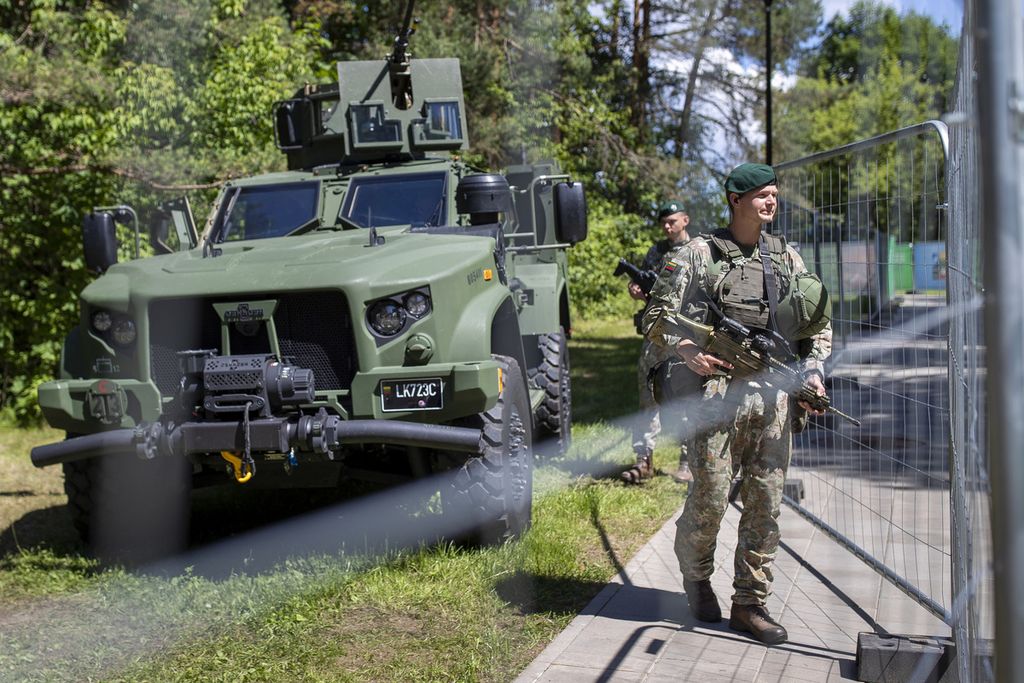 Anggota militer Lituania berjaga di balik pagar yang mengelilingi lokasi penyelenggaraan KTT NATO di Ibu Kota Lituania, Vilnius, (9/7/2023). Salah satu hal yang menjadi diskusi hangat selama KTT ialah pengiriman bom tandan untuk Ukraina.