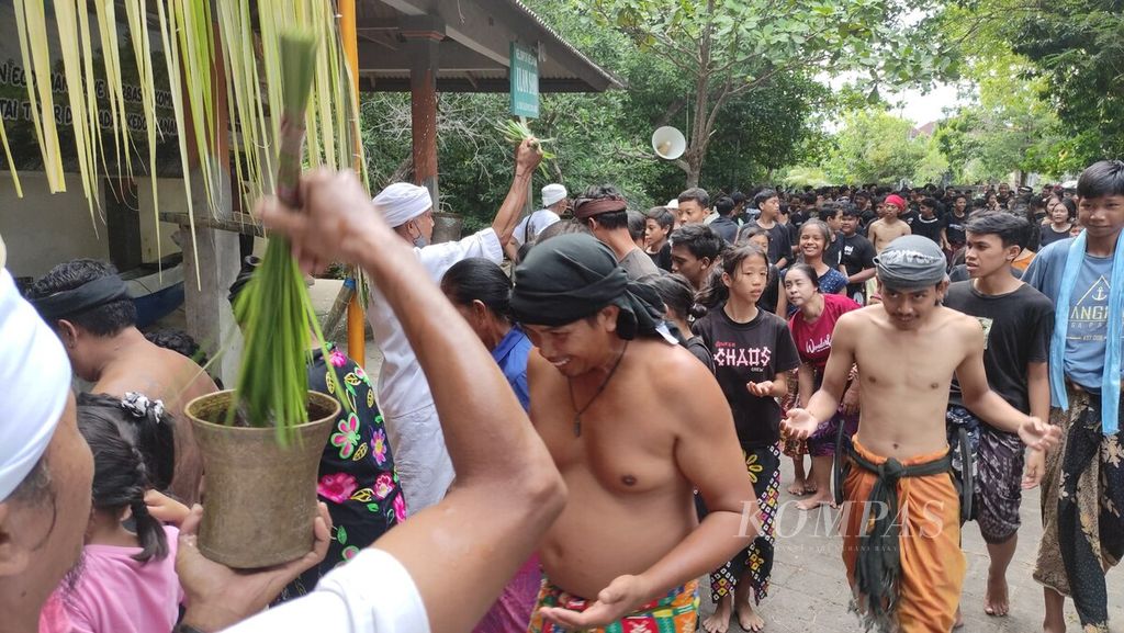 <i>Krama </i>(warga) dan <i>yowana </i>(pemuda dan pemudi) Desa Adat Kedonganan, Kedonganan, Kuta, Kabupaten Badung, menerima tirta (air suci) yang dipercikkan <i>jero pamangku </i>sebelum mengikuti tradisi <i>mabuug-buugan </i>di tengah hutan mangrove Taman Hutan Raya Ngurah Rai, Kamis (23/3/2023).