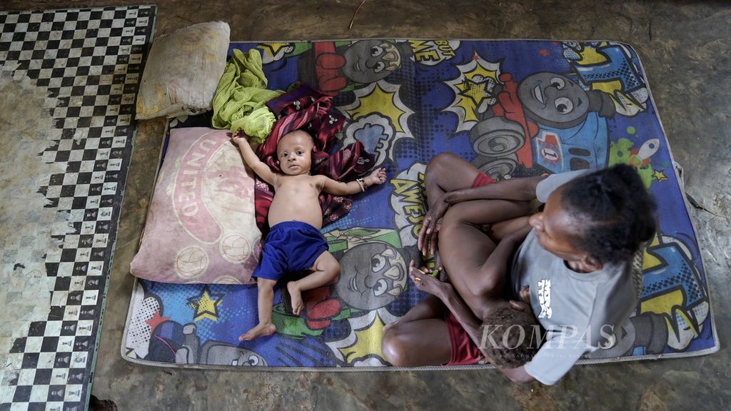 Demianus Gebze lying on a thin carpet next to his mother Dorce Gebze (30) in Zanegi Village, Animha District, Merauke Regency, Papua, Thursday (11/10/2022). The six-month-old child of the Zanegi Village Head is undernourished.