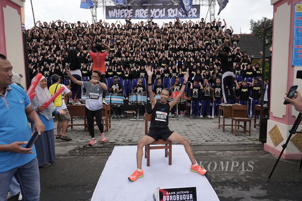 Seorang pelari berpose sejenak di depan koreografi siswa SMP 2 Mungkid saat berpartisipasi dalam Bank Jateng Borobudur Marathon 2024, Minggu (1/12/2024). Borobudur Marathon 2024 diikuti oleh 10.500 pelari dalam tiga kategori, yaitu lari maraton, setengah maraton, dan 10 kilometer. 