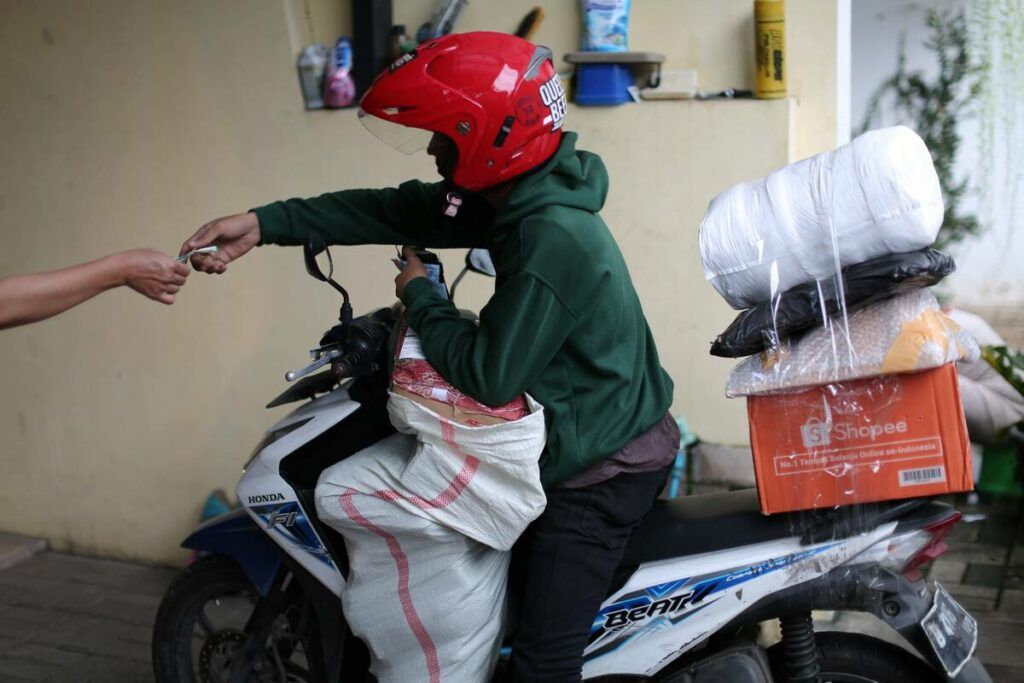 Jasa pengiriman menerima uang dari pembelian paket via aplikasi Shopee di Pondok Kelapa, Jakarta Timur, Senin (18/5/2020). Pembatasan sosial berskala besar yang diterapkan saat pandemi Covid-19 memaksa warga berada di rumah saja, sambil tetap beraktivitas, seperti bekerja, belajar, ataupun beribadah. Membeli berbagai barang yang dibutuhkan, baik kebutuhan sehari-hari maupun barang sekunder lainnya, juga harus dilakukan secara dalam jaringan (daring/online).