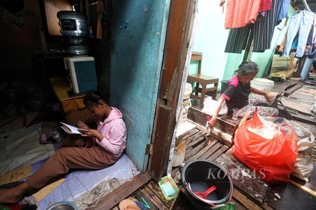 Nuraini, siswi SD kelas 6 sedang mengerjakan tugas sekolah di rumahnya yang berada di kawasan hunian semipermanen padat penduduk yang berada di antara jalur kereta di Pademangan, Jakarta Utara, Senin (6/12/2021). Karena Covid-19, Nuraini hanya seminggu sekali melaksanakan pembelajaran tatap muka terbatas, selebihnya dilakukannya secara daring.
