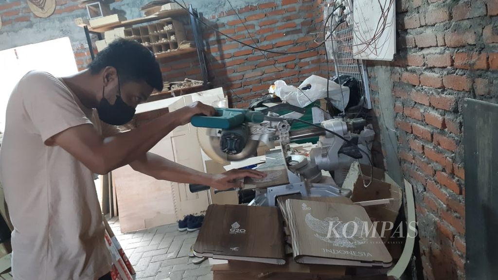 Proses pemotongan kayu menggunakan mesin pemotong otomatis untuk kerajinan tempat penyimpanan buku atau binder di bengkel kerja Hucravindo, salah satu industri kecil menengah kerajinan kayu di Sidoarjo, Jawa Timur, Senin (7/11/2022). 